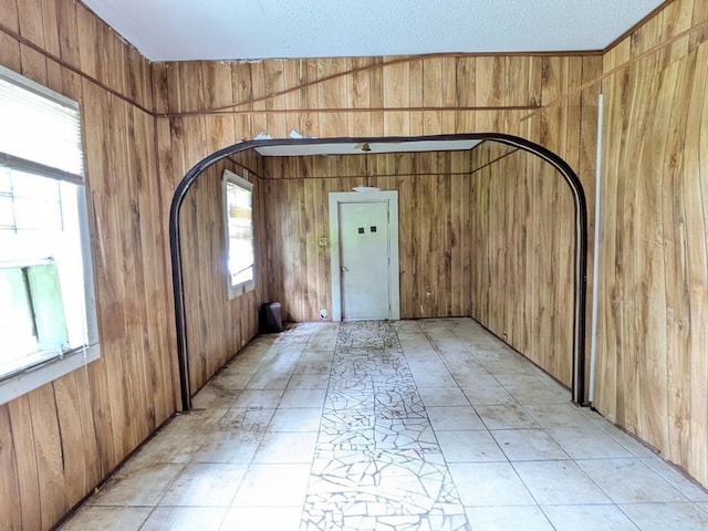 spare room with a textured ceiling and wooden walls