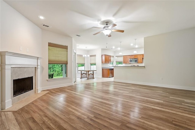 unfurnished living room with a fireplace, light wood-type flooring, and ceiling fan