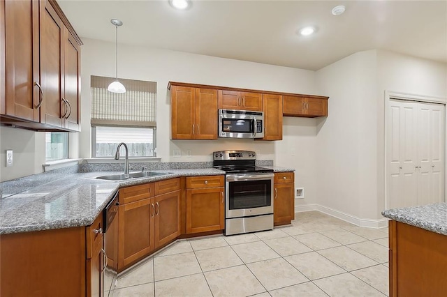 kitchen with pendant lighting, sink, light tile patterned floors, light stone countertops, and appliances with stainless steel finishes