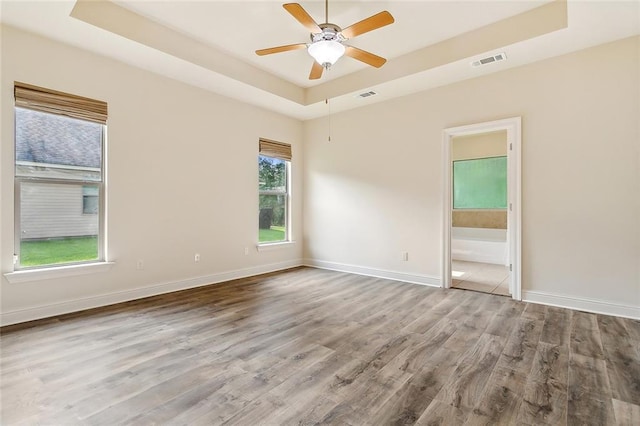 unfurnished room featuring hardwood / wood-style floors, ceiling fan, and a raised ceiling