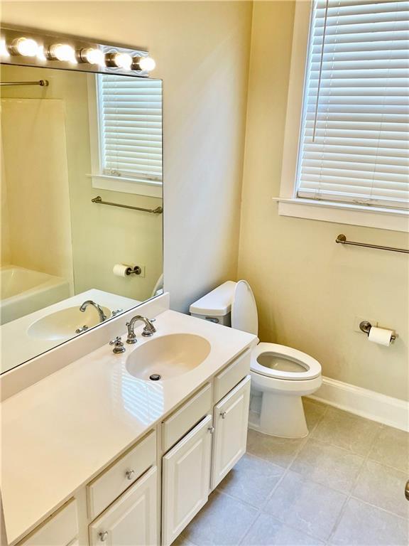 bathroom featuring toilet, vanity, tile patterned floors, and a bathing tub