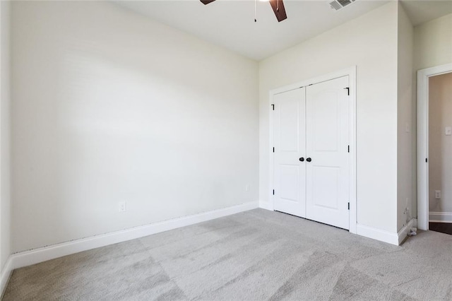 unfurnished bedroom featuring a closet, light colored carpet, and ceiling fan