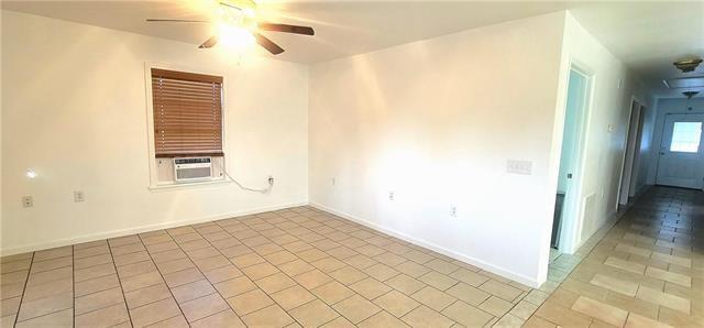 tiled empty room featuring ceiling fan and cooling unit