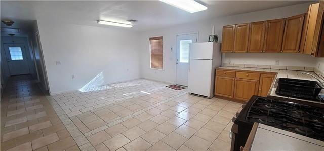 kitchen with white fridge, sink, black range with gas cooktop, and light tile patterned flooring