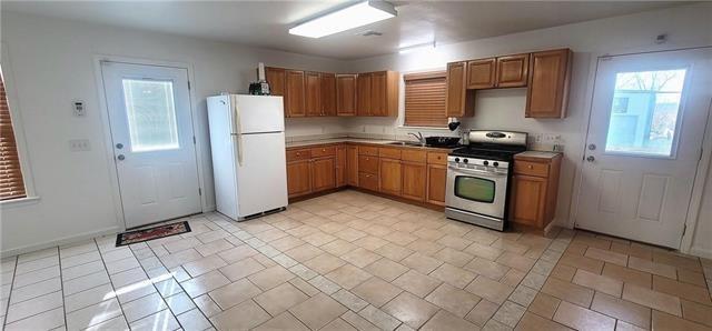 kitchen featuring white refrigerator, stainless steel gas range oven, and sink