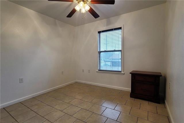 tiled spare room with ceiling fan