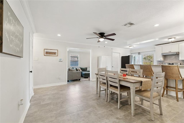 tiled dining area with ceiling fan and ornamental molding