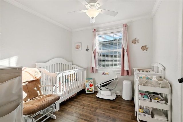 bedroom with crown molding, ceiling fan, dark wood-type flooring, and a nursery area