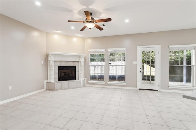 unfurnished living room with a tile fireplace, a wealth of natural light, ceiling fan, and light tile patterned flooring