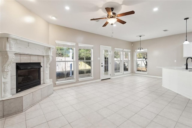 unfurnished living room with a tile fireplace, light tile patterned floors, plenty of natural light, and ceiling fan