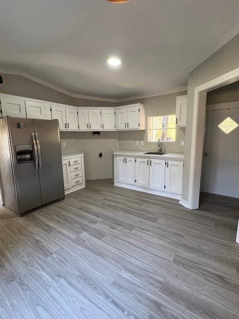 kitchen featuring stainless steel fridge, light hardwood / wood-style flooring, white cabinetry, and lofted ceiling