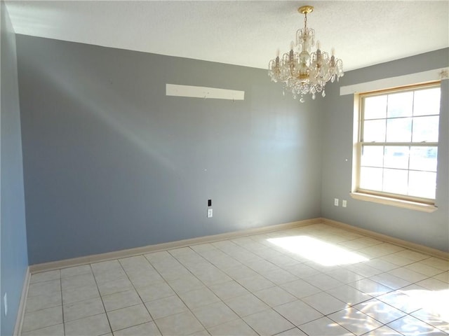 tiled spare room with a chandelier