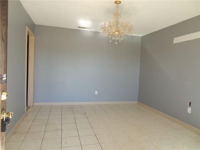 spare room with a chandelier and light tile patterned floors