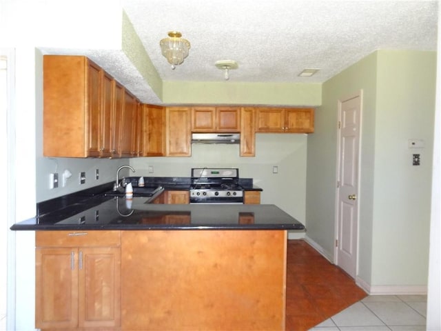 kitchen with black gas stove, sink, light tile patterned floors, a textured ceiling, and kitchen peninsula