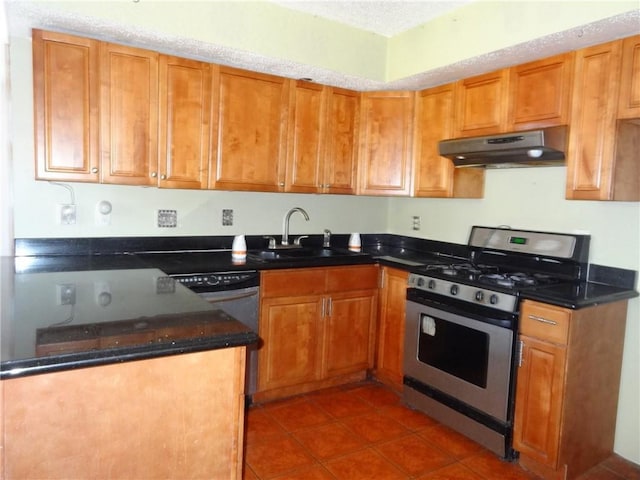 kitchen featuring dishwashing machine, sink, dark tile patterned floors, and stainless steel gas range