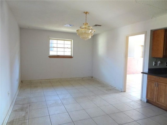 empty room featuring light tile patterned floors and an inviting chandelier