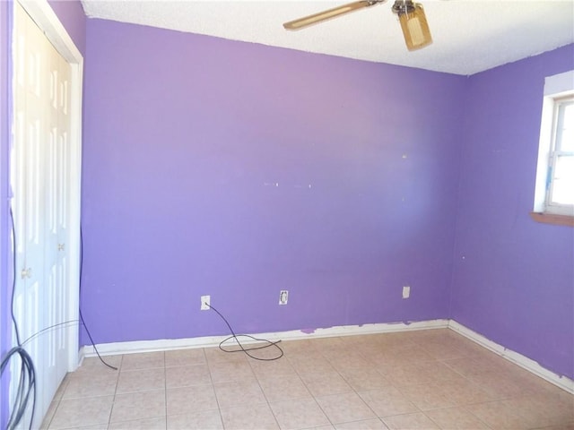 unfurnished room with ceiling fan, light tile patterned floors, and a textured ceiling