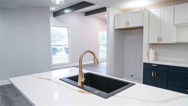 kitchen with kitchen peninsula, stainless steel gas stove, white cabinetry, and sink