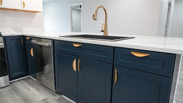 kitchen featuring blue cabinets, sink, light hardwood / wood-style flooring, stainless steel dishwasher, and kitchen peninsula