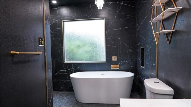 bathroom with plenty of natural light, a bathtub, toilet, and tile walls