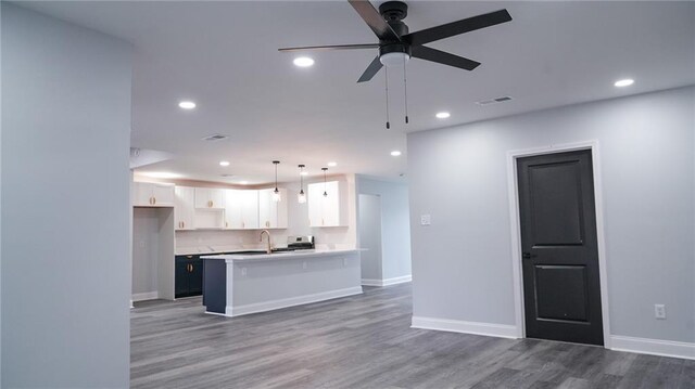 kitchen with pendant lighting, a kitchen breakfast bar, ceiling fan, dark hardwood / wood-style flooring, and white cabinetry