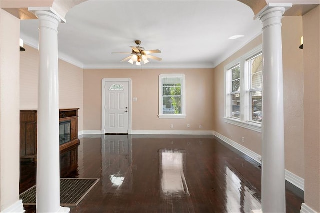 unfurnished living room featuring dark hardwood / wood-style flooring, a large fireplace, ornate columns, and crown molding