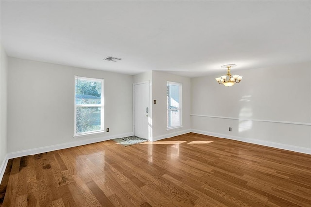 empty room with hardwood / wood-style floors and a notable chandelier