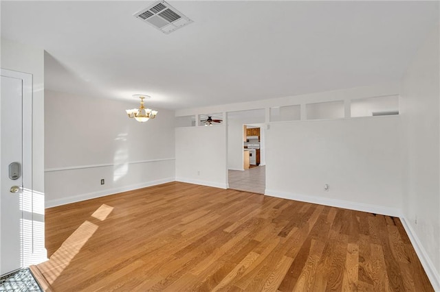 spare room featuring ceiling fan with notable chandelier and hardwood / wood-style flooring