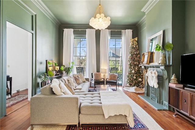 living room featuring an inviting chandelier, ornamental molding, and light hardwood / wood-style flooring