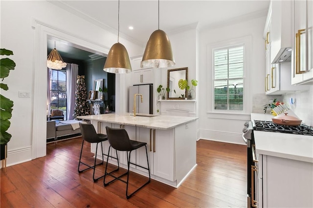 kitchen featuring a kitchen island with sink, white cabinets, sink, gas range, and dark hardwood / wood-style flooring