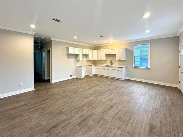 unfurnished living room with dark hardwood / wood-style flooring, ornamental molding, and sink