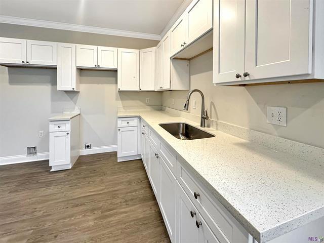 kitchen featuring dark wood-type flooring, white cabinets, sink, ornamental molding, and light stone counters