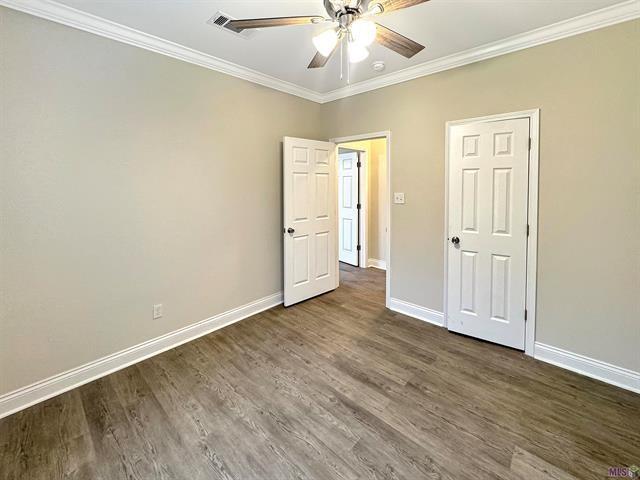 unfurnished bedroom with ceiling fan, dark hardwood / wood-style flooring, and ornamental molding