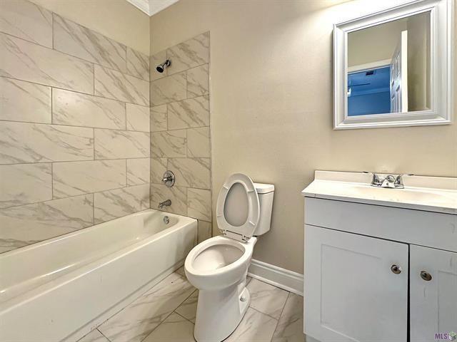 full bathroom featuring tiled shower / bath combo, toilet, and vanity