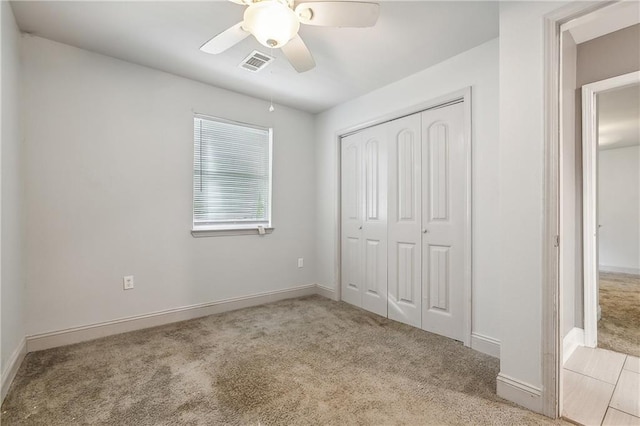 unfurnished bedroom with ceiling fan, a closet, and light carpet