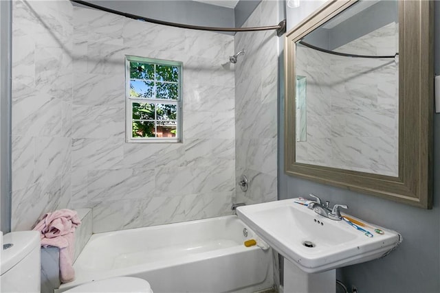 full bathroom featuring tiled shower / bath combo, toilet, and sink