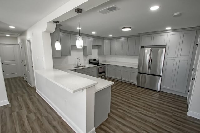 kitchen with kitchen peninsula, appliances with stainless steel finishes, dark hardwood / wood-style flooring, sink, and decorative light fixtures