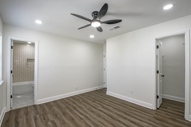 unfurnished bedroom with connected bathroom, ceiling fan, dark hardwood / wood-style flooring, and a walk in closet