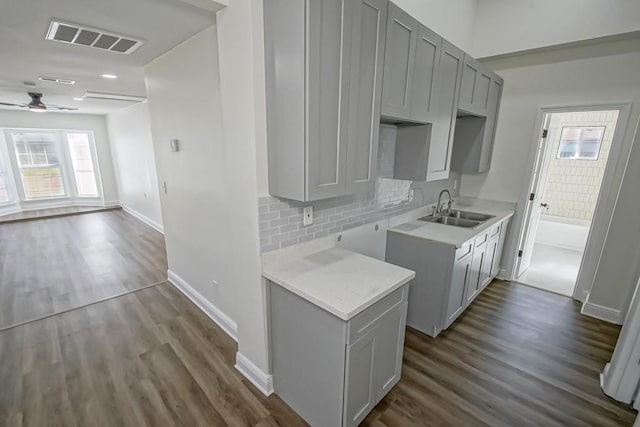 kitchen featuring ceiling fan, sink, dark wood-type flooring, tasteful backsplash, and gray cabinets