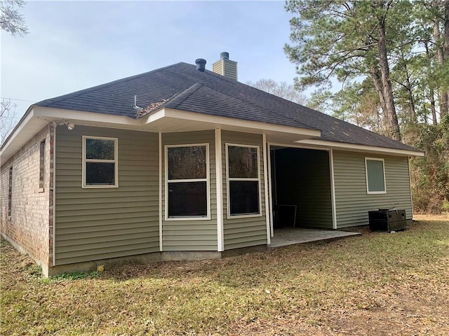 rear view of property with cooling unit and a yard