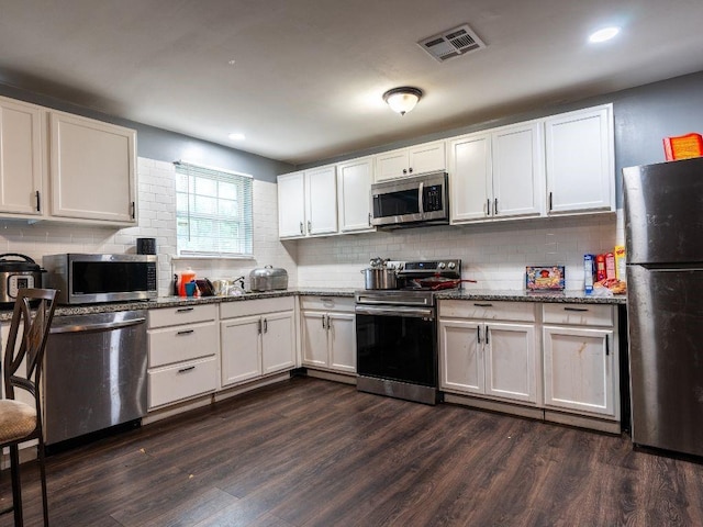 kitchen featuring white cabinets, stainless steel appliances, dark wood-type flooring, and dark stone countertops