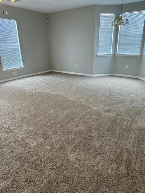 spare room with carpet flooring and ceiling fan with notable chandelier