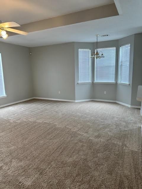 spare room with carpet floors and ceiling fan with notable chandelier