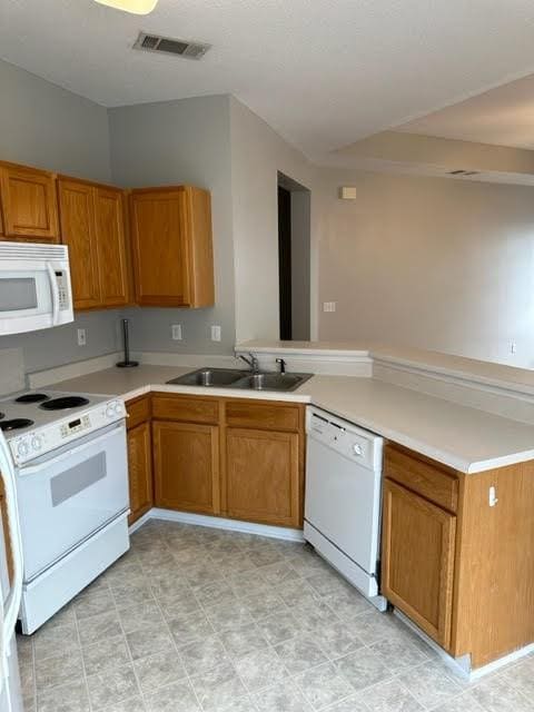 kitchen featuring kitchen peninsula, white appliances, and sink