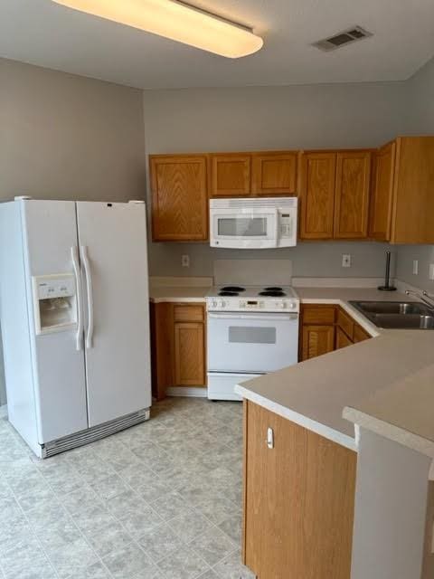 kitchen with kitchen peninsula, white appliances, and sink