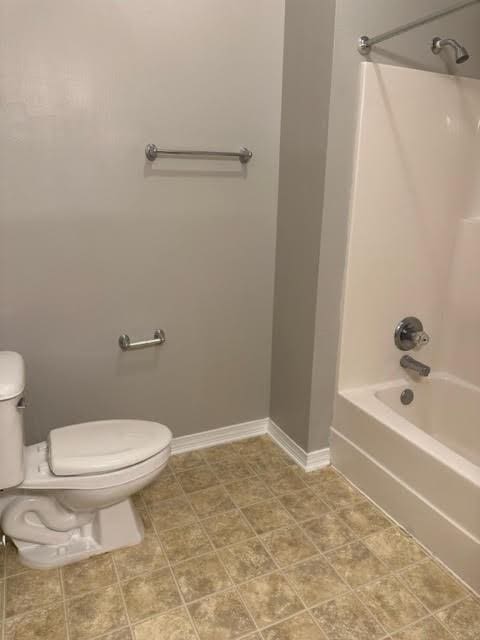 bathroom featuring tile patterned flooring, bathtub / shower combination, and toilet