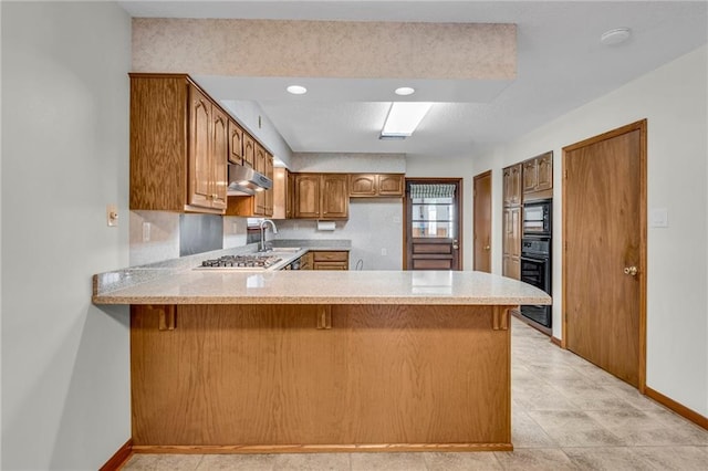 kitchen with black appliances, kitchen peninsula, sink, and light tile patterned floors