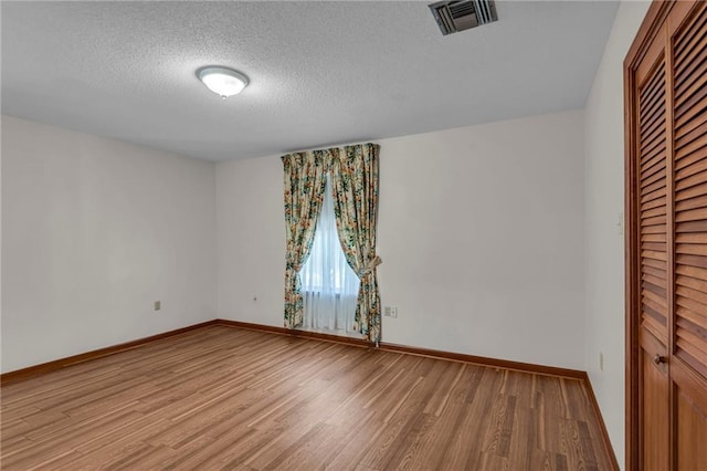 empty room featuring light hardwood / wood-style floors and a textured ceiling