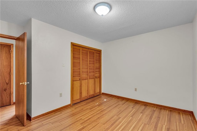 unfurnished bedroom featuring a textured ceiling, light wood-type flooring, and a closet