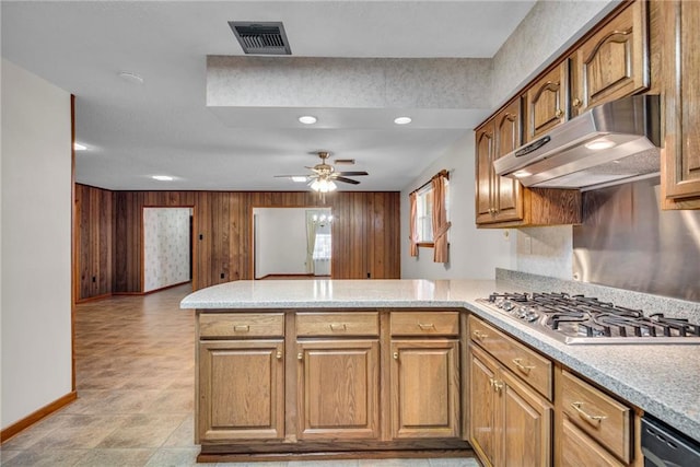 kitchen with kitchen peninsula, stainless steel appliances, ceiling fan, and wood walls